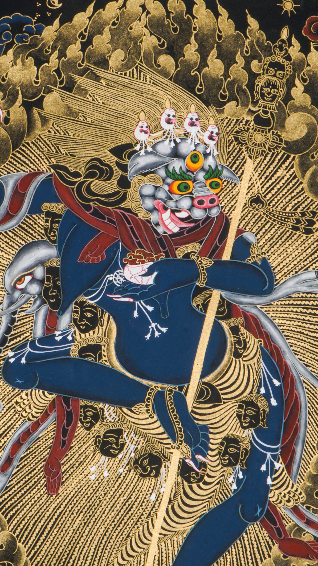 Traditional Tibetan thangka painting depicting Singh Mukhi, the lion-faced protector dakini, shown in a dynamic dancing pose on a lotus base, surrounded by radiant gold flames and intricate symbolic patterns on a dark background.