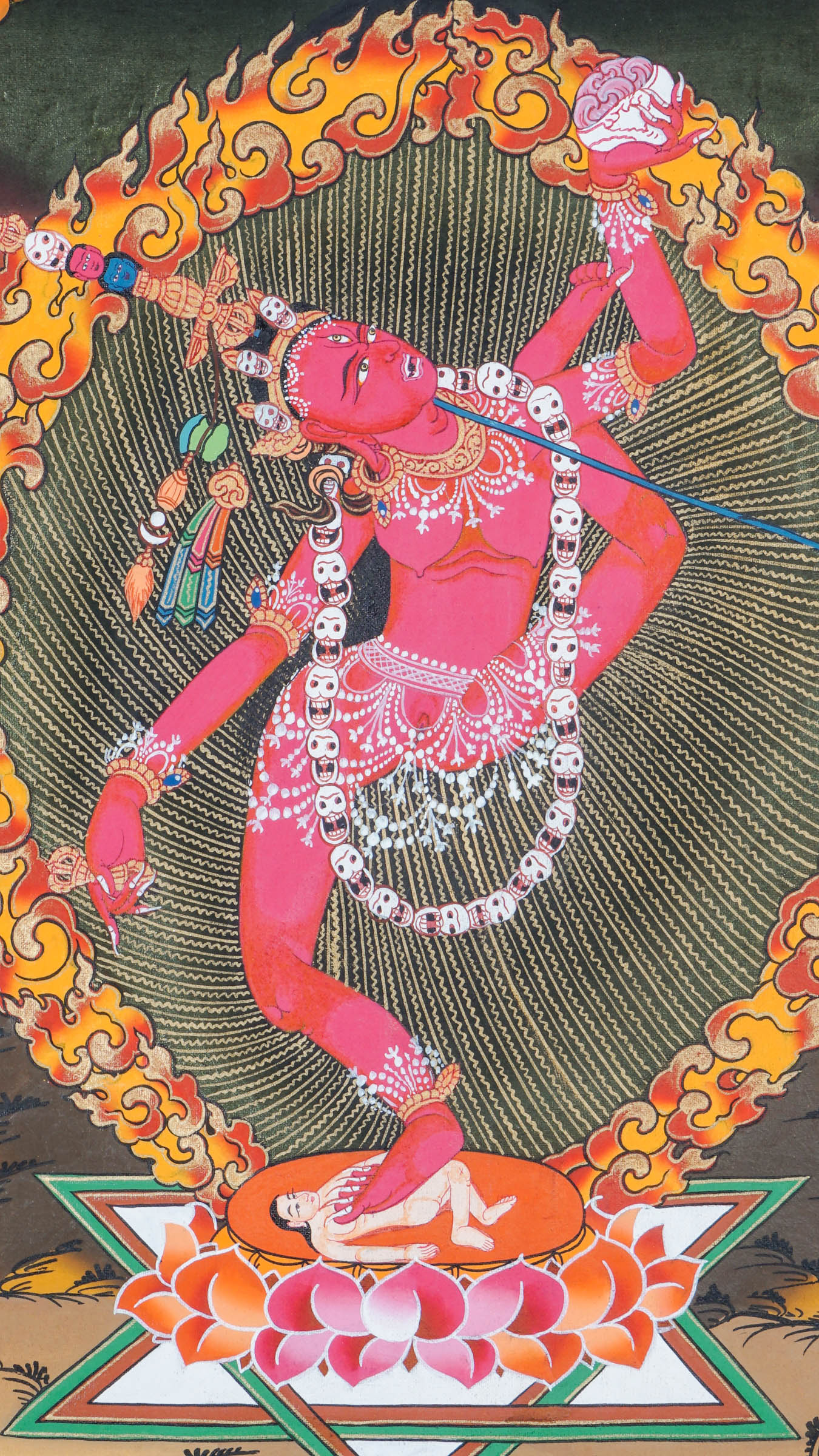 Traditional Tibetan thangka painting depicting Vajrayogini in a dynamic dancing pose on a lotus throne, encircled by flames and clouds, holding ritual implements against a warm, mountainous landscape.