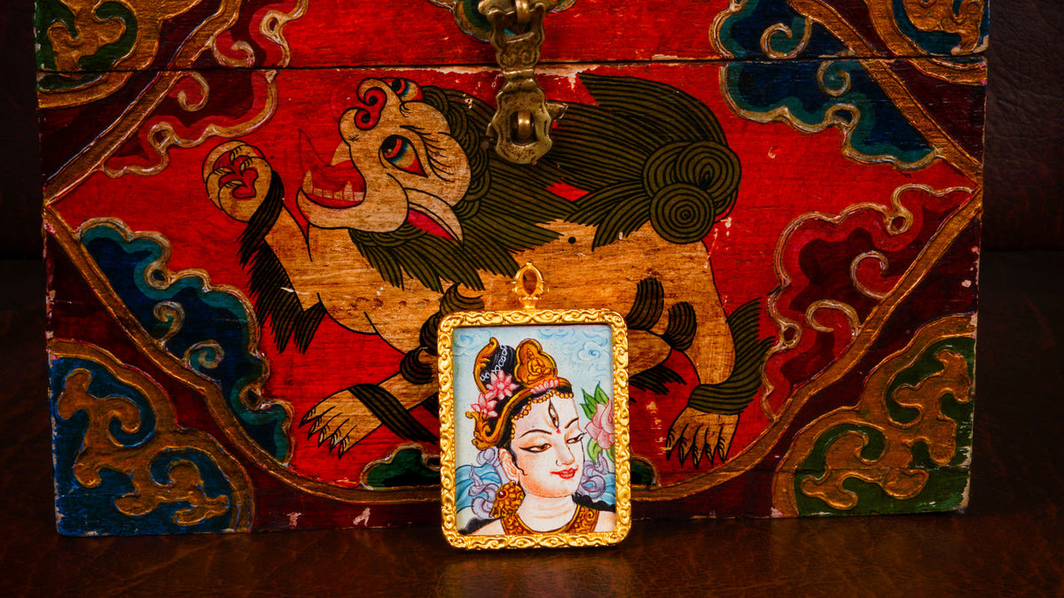 White Tara Ghau pendant featuring a miniature Tibetan Buddhist goddess of compassion artwork in a decorative gold-tone frame handcrafted in Nepal.
