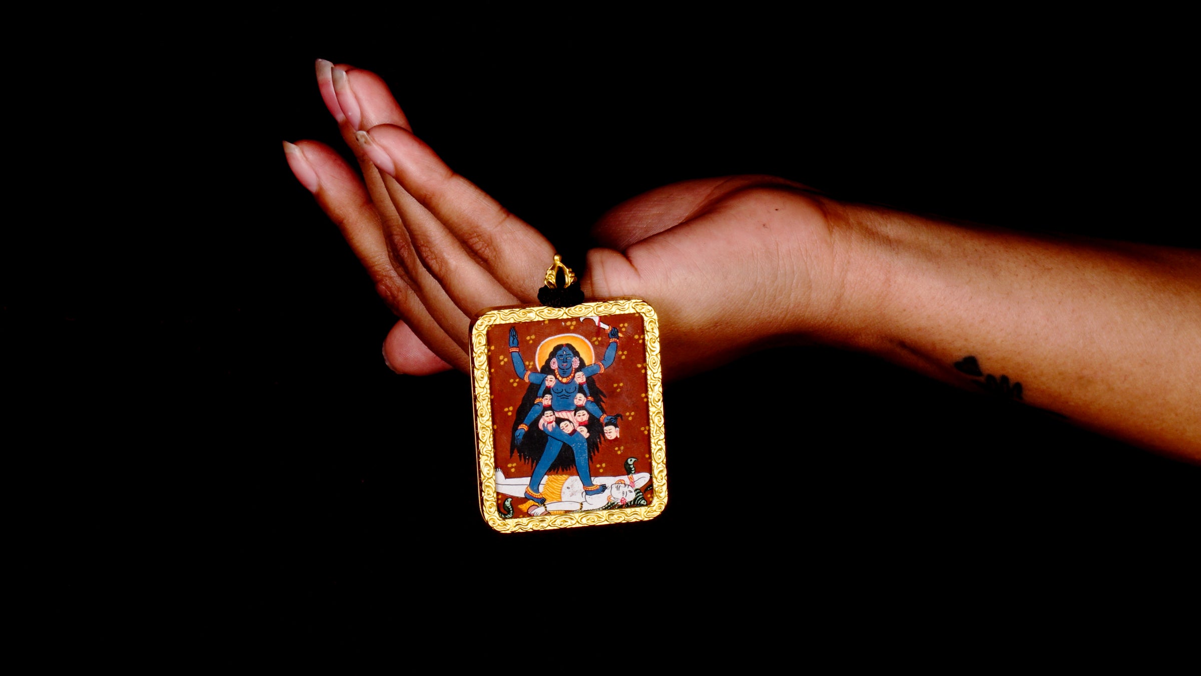 Hand-painted Goddess Kali miniature Thangka pendant in gold-accented copper Ghau locket with black beaded cord.