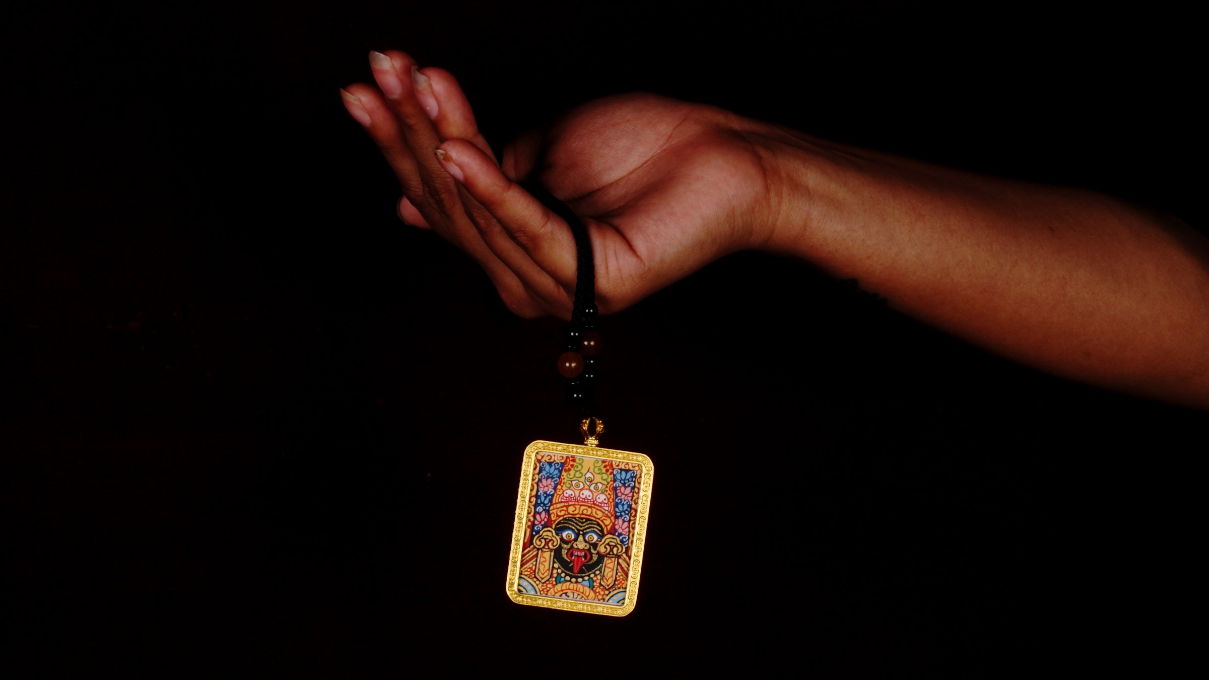 Hand-painted Goddess Kali miniature Thangka pendant in gold-accented copper Ghau locket with black beaded cord.
