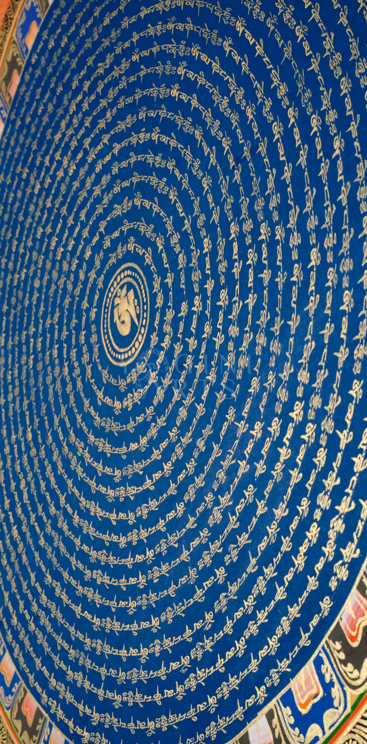 Blue Om Mantra Mandala thangka featuring sacred Om symbol surrounded by concentric circles of gold Tibetan mantra calligraphy and floral corner motifs.