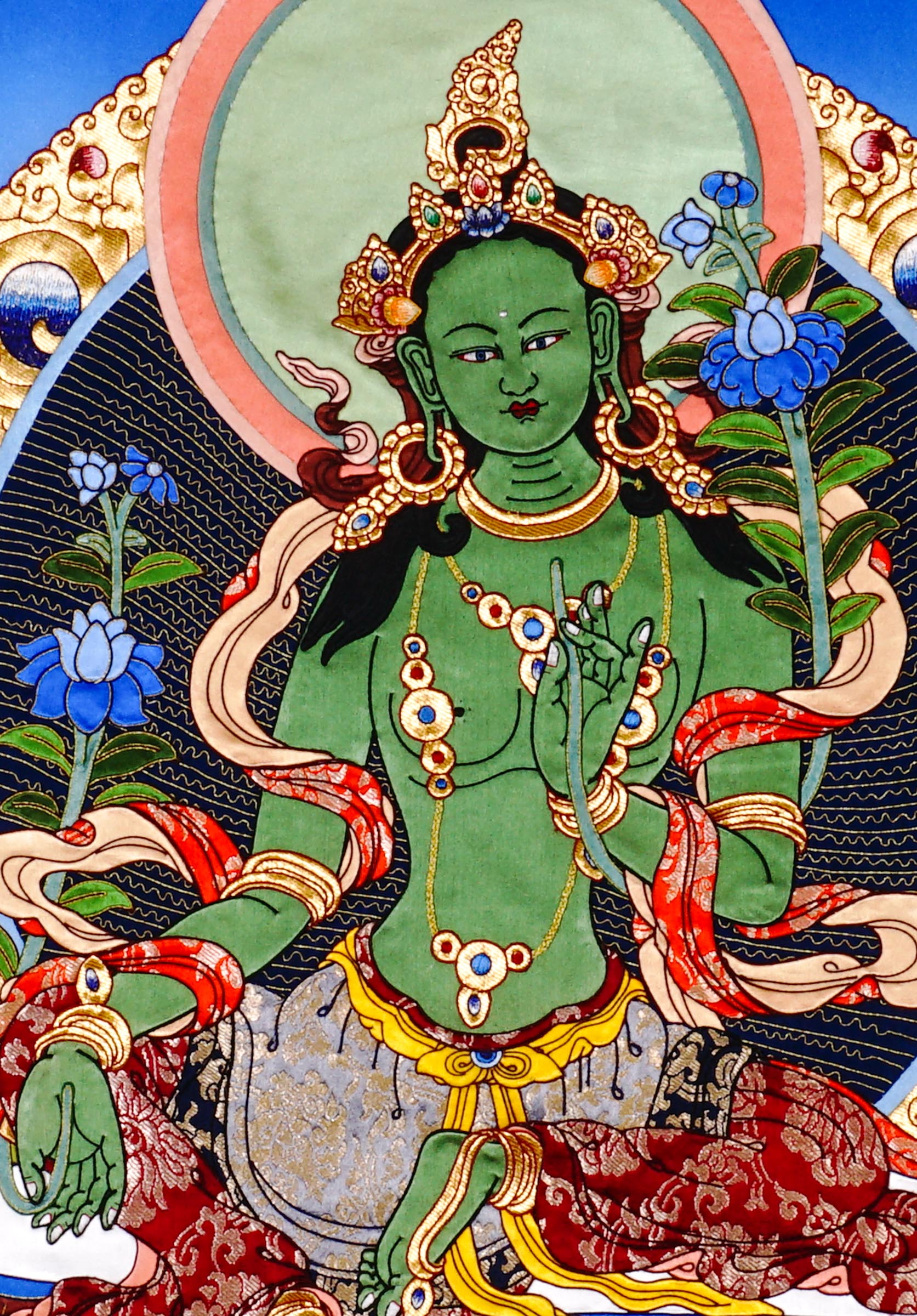 Green Tara cloth thangka printed on fabric showing Tibetan Buddhist goddess seated on lotus holding blue utpala lotus with vibrant halo background.