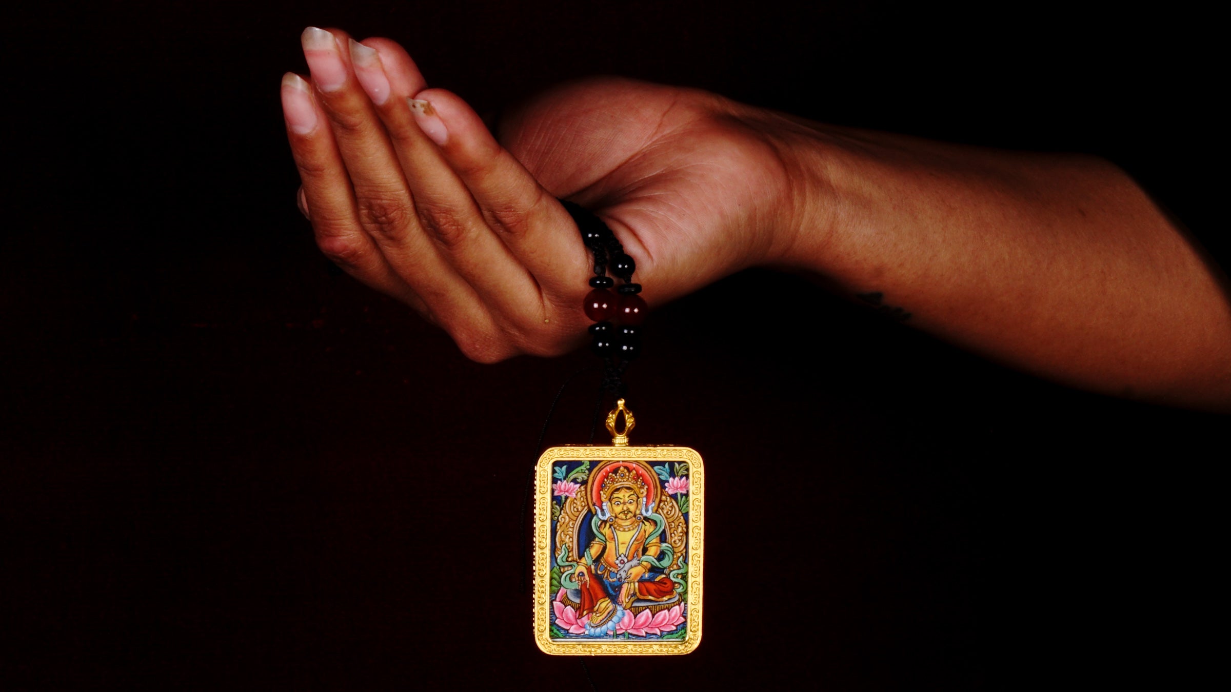 Hand-painted Yellow Zambala miniature Thangka pendant in gold-accented copper Ghau locket with black beaded cord.