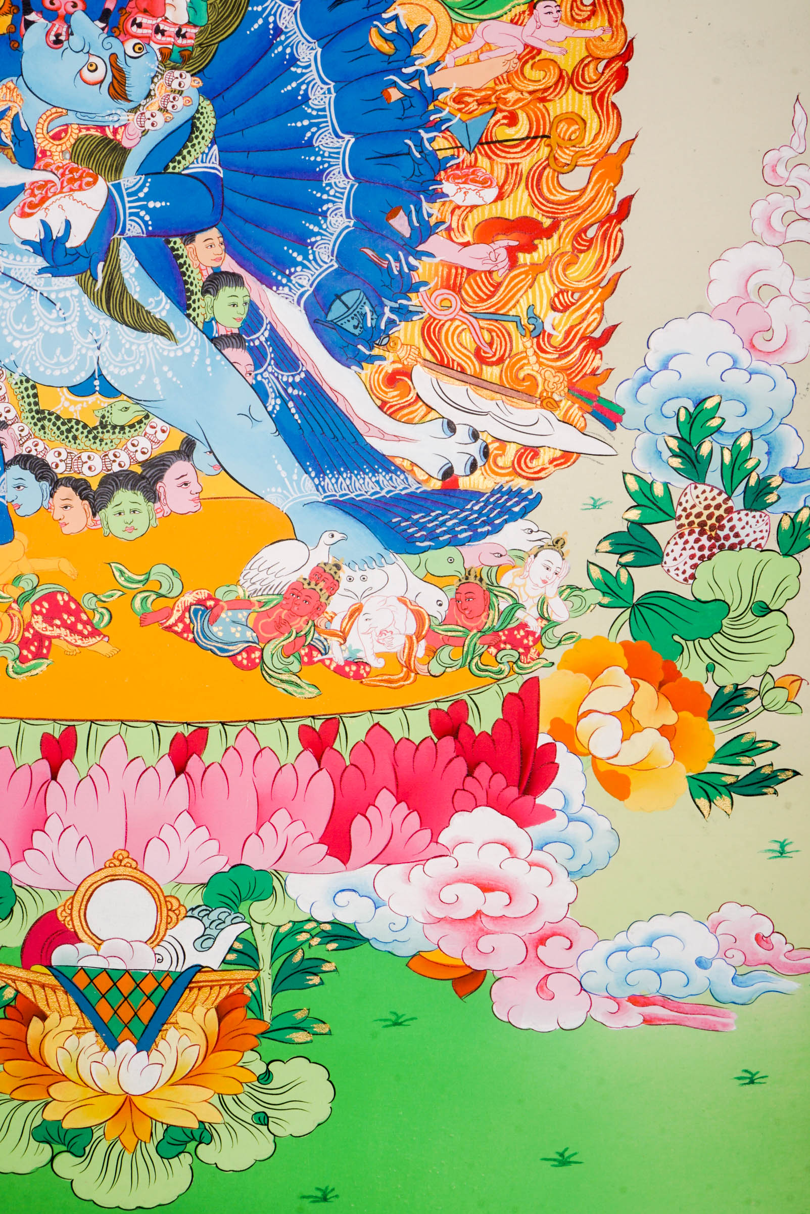 Traditional Tibetan thangka painting depicting Yamantaka Shakti in dynamic embrace, surrounded by flames, clouds, and abundant floral motifs, rendered in vivid colors against a green and turquoise landscape.