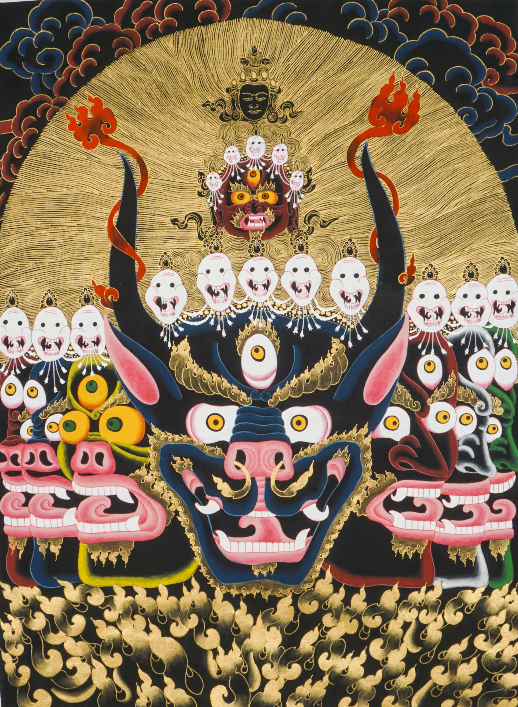 Thangka painting showing a large blue multi-faced figure with numerous eyes and open mouths, crowned by smaller faces and skull motifs, set against a gold halo and stylized cloud background.