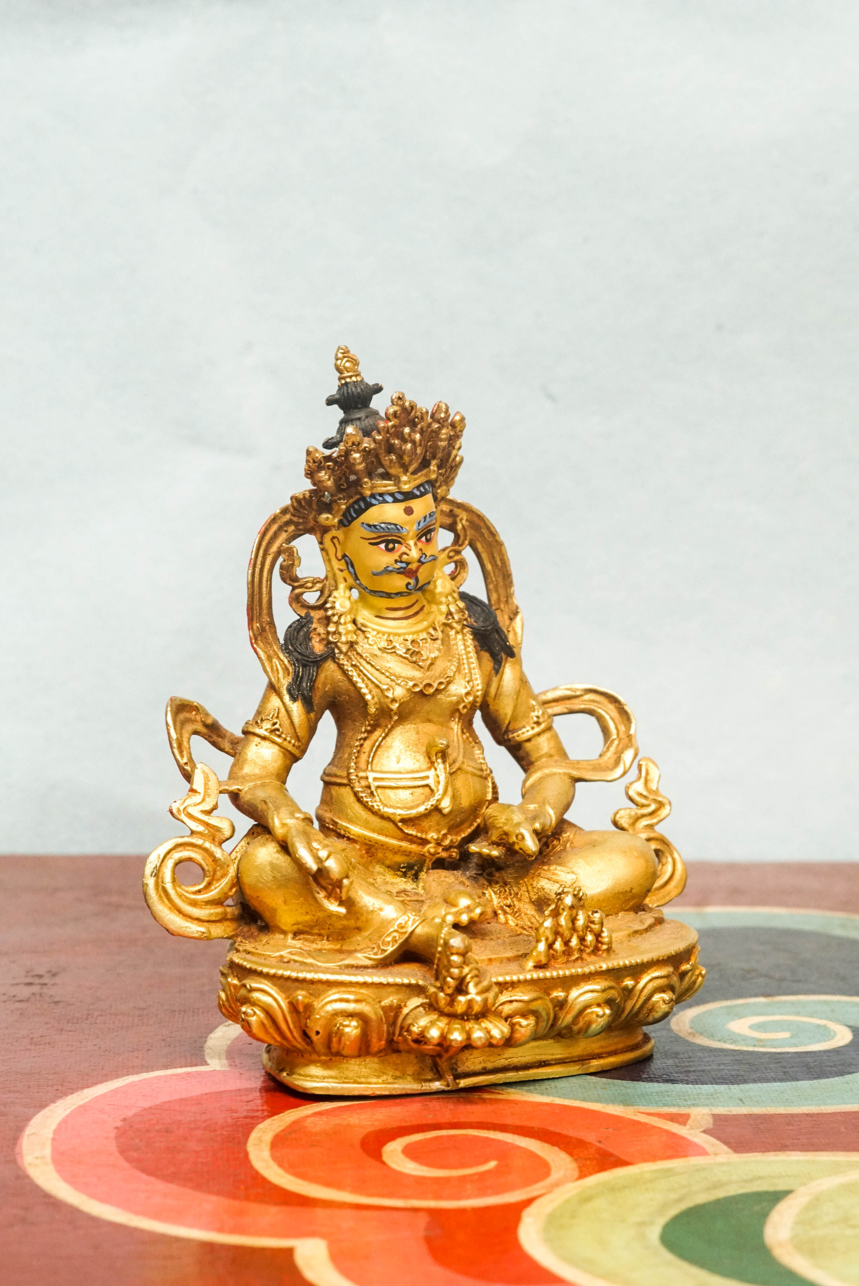 Handmade gold Zambala statue adorned with crown and jewelry, symbolizing prosperity and removal of obstacles.
