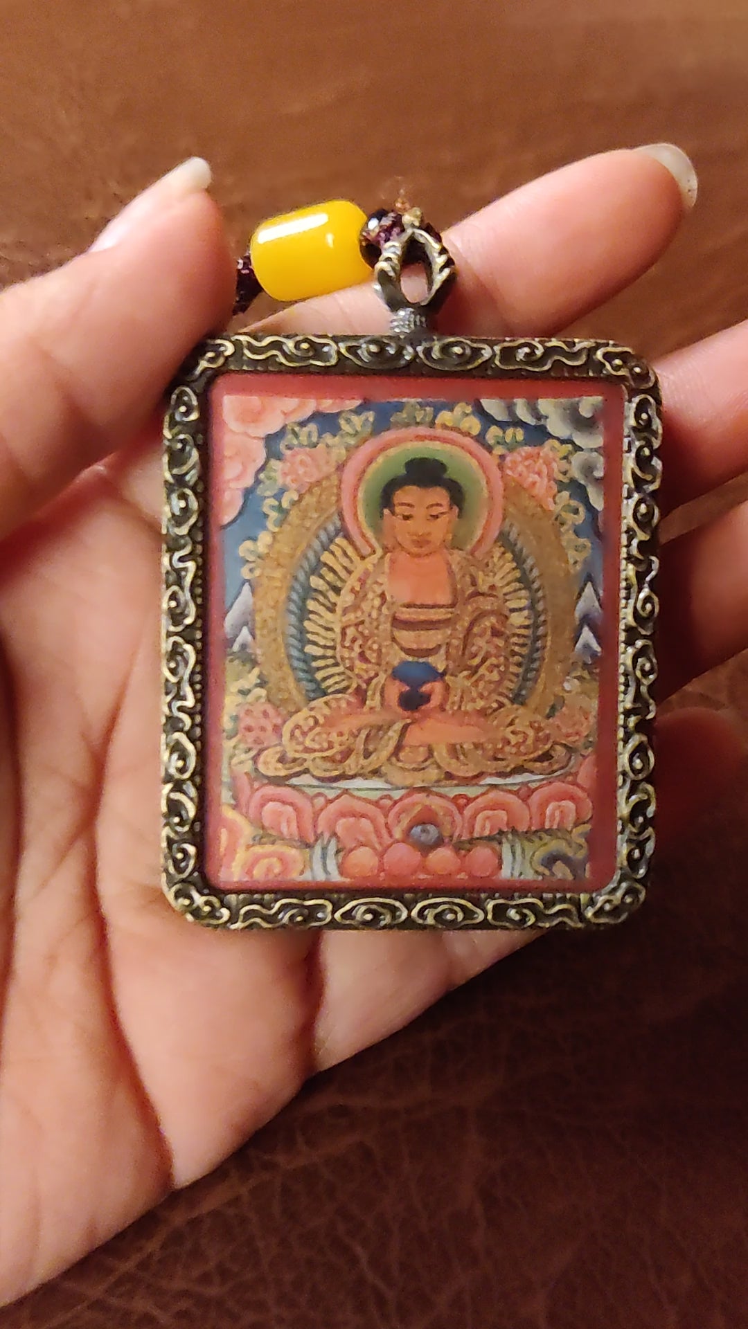 Hand-painted Amitabha Buddha Ghau pendant in an antique silver-tone frame, handcrafted in Nepal using traditional Himalayan miniature painting techniques.