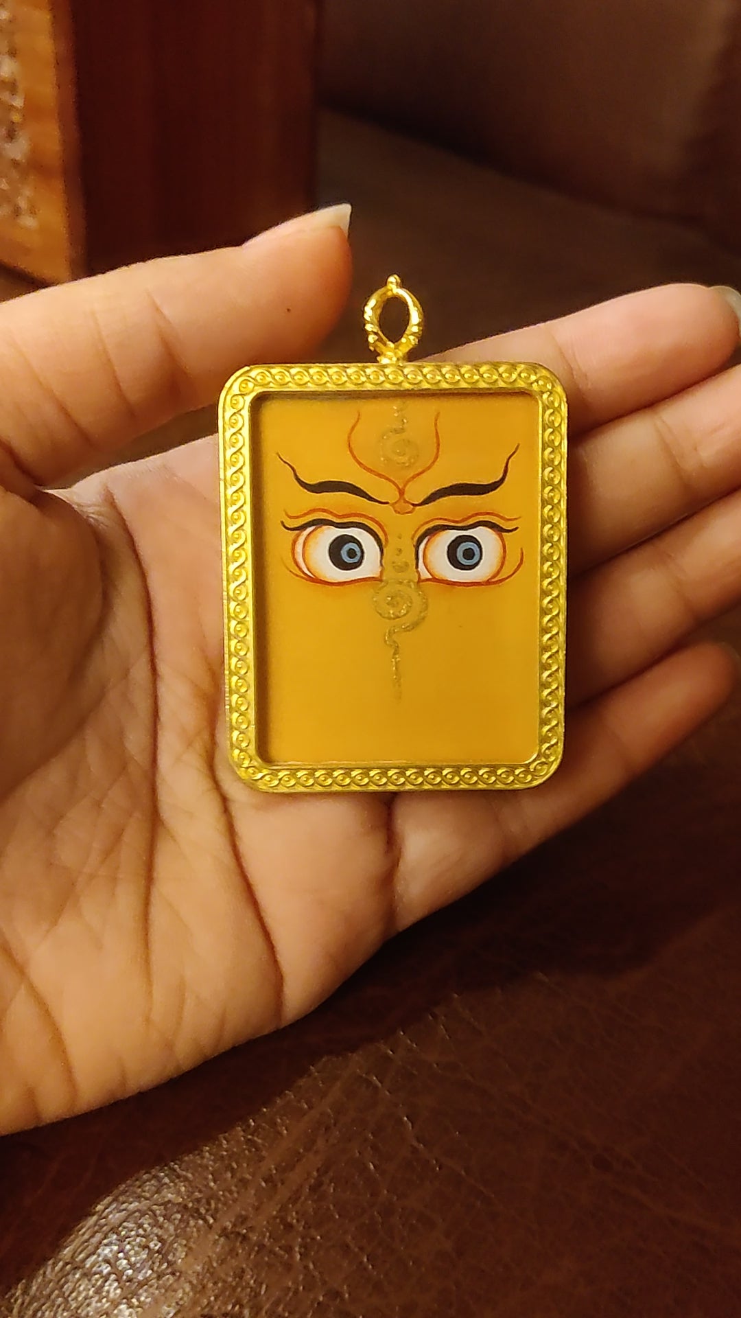 Hand-painted Zambhala Eyes Ghau pendant with sacred Buddha Wisdom Eyes in a handcrafted gold-tone frame made in Nepal.