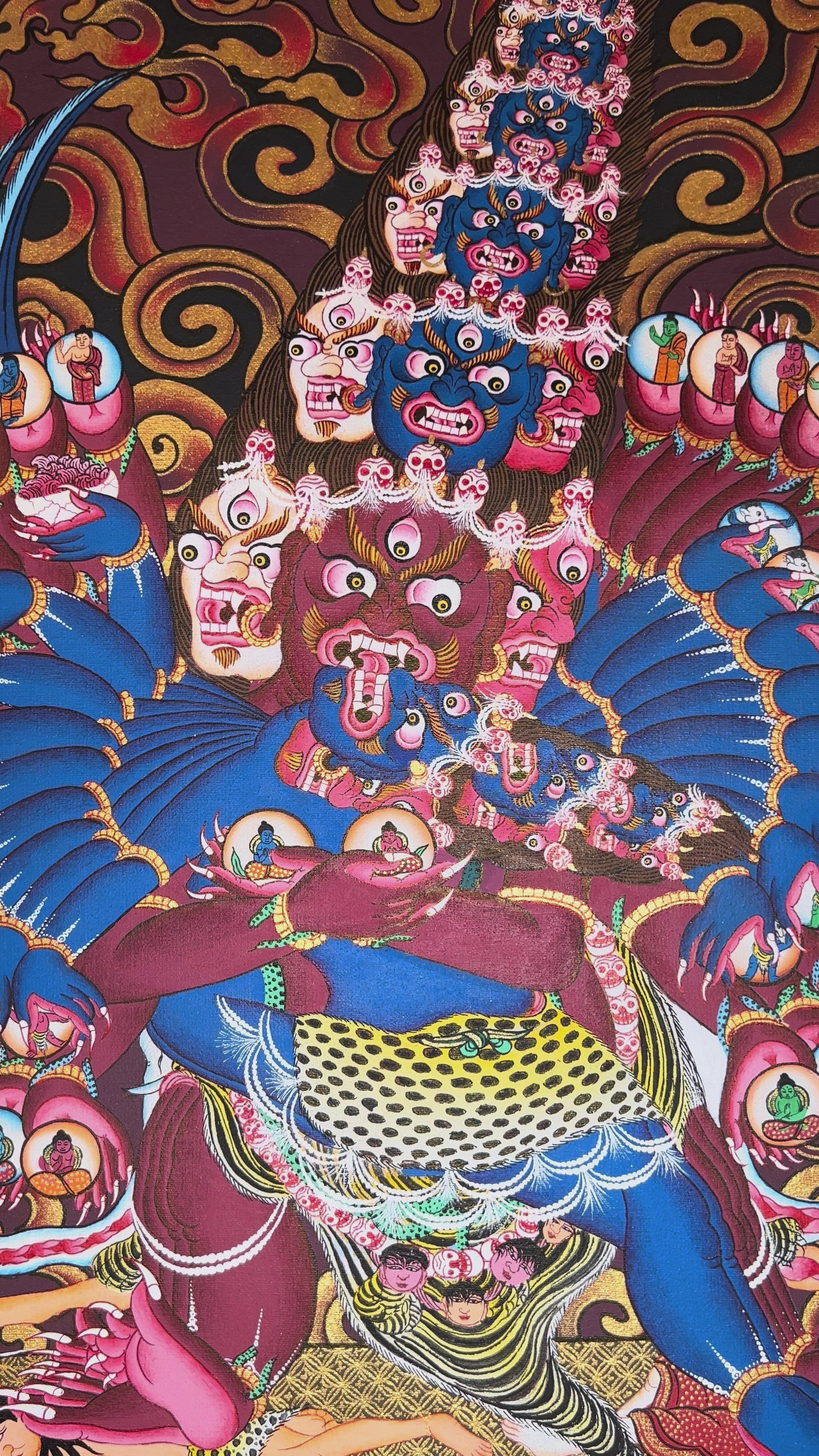 Heruka thangka showing a multi-headed, multi-armed wrathful tantric deity dancing on figures, surrounded by flames and intricate symbolic elements.