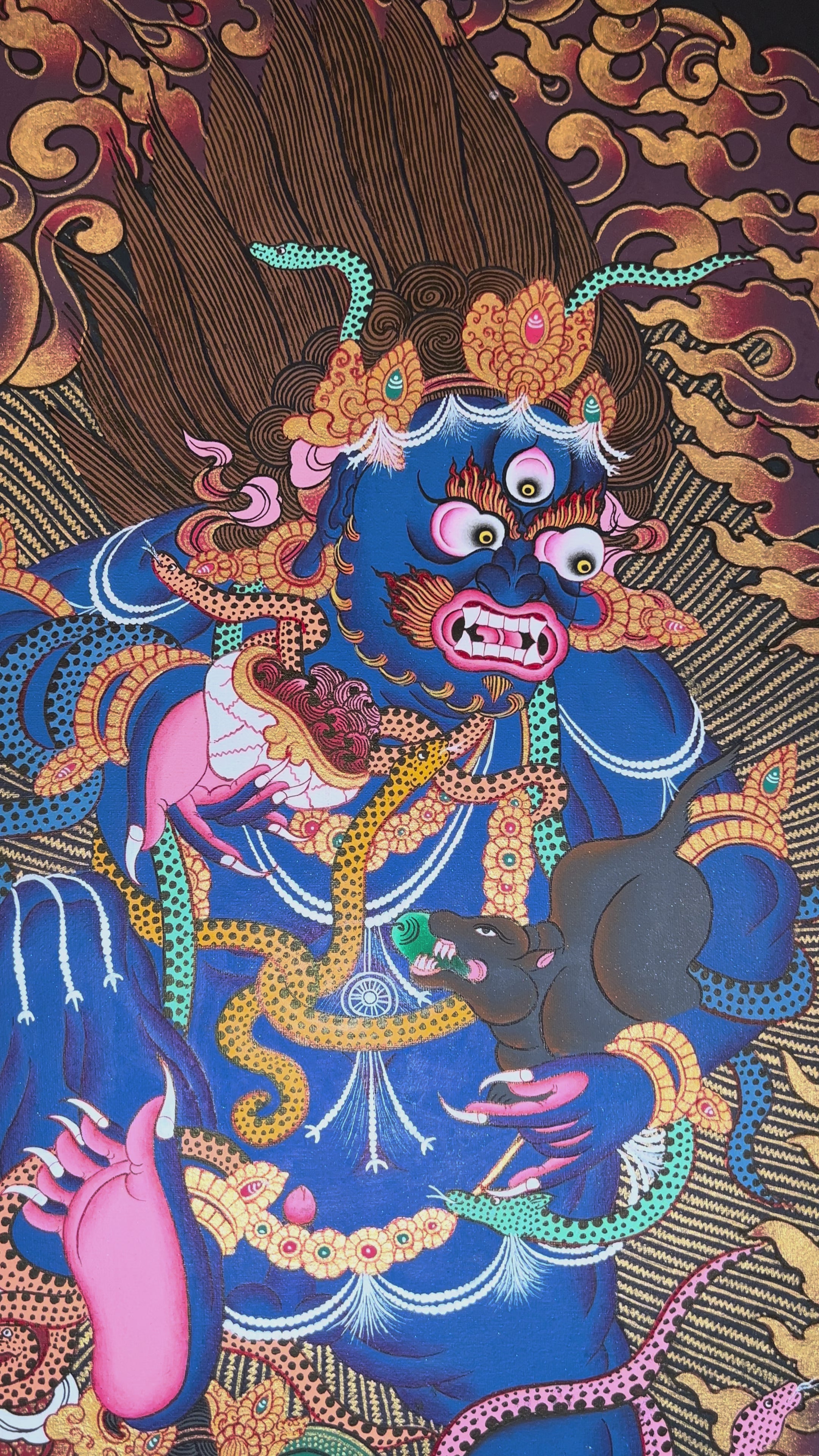 Black Dzambhala thangka showing a wrathful dark blue deity holding a mongoose, surrounded by flames and standing on subdued figures in Tibetan Buddhist style.