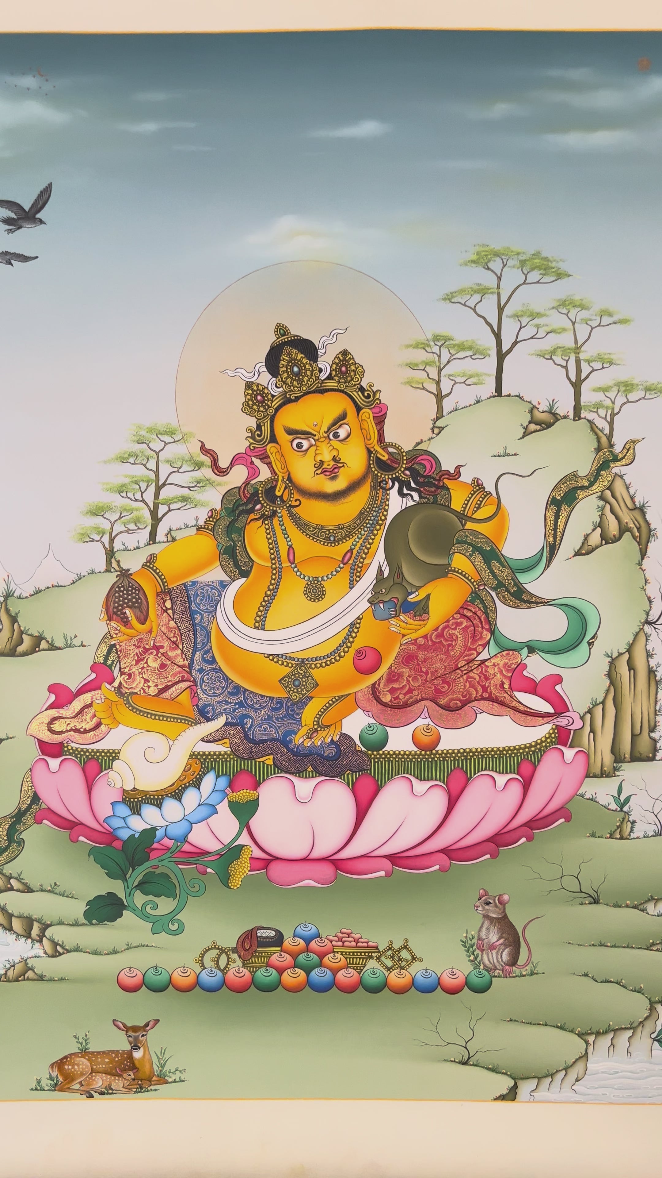 Hand-painted Yellow Dzambhala thangka showing Tibetan wealth deity seated on lotus throne holding mongoose and citron with gold detailing and Himalayan landscape background.