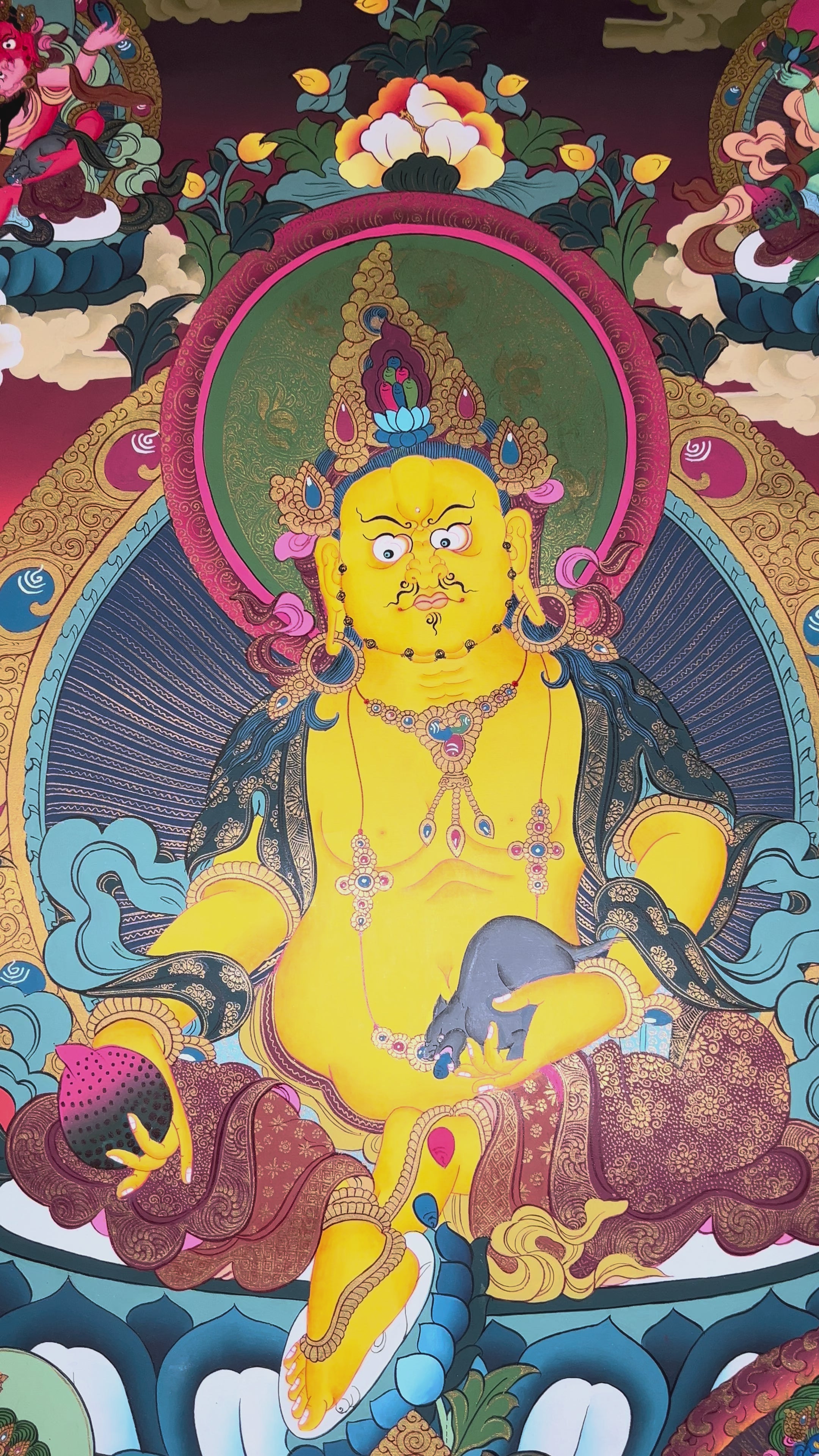 Colorful Yellow Zambhala thangka depicting the Buddhist wealth deity holding a mongoose and jewel vase.