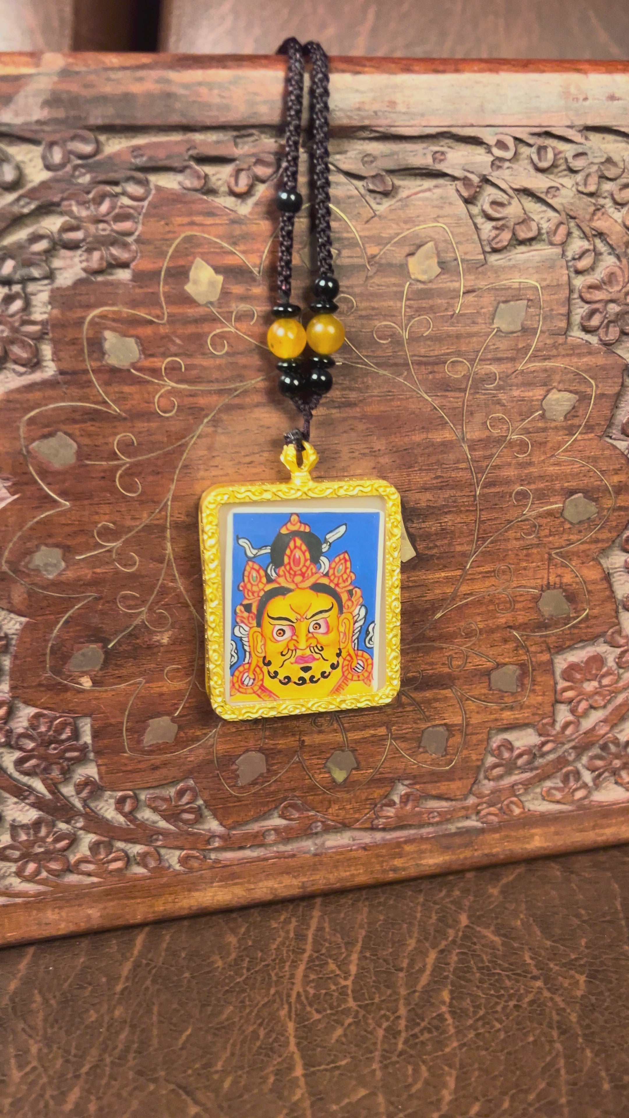 Hand-painted Zambala wealth deity miniature Thangka pendant in gold-accented copper Ghau locket with black beaded cord.