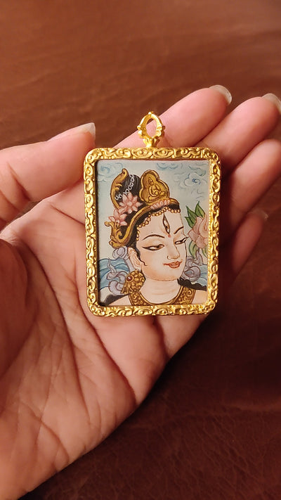 White Tara Ghau pendant featuring a miniature Tibetan Buddhist goddess of compassion artwork in a decorative gold-tone frame handcrafted in Nepal.