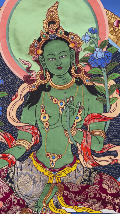Green Tara cloth thangka printed on fabric showing Tibetan Buddhist goddess seated on lotus holding blue utpala lotus with vibrant halo background.