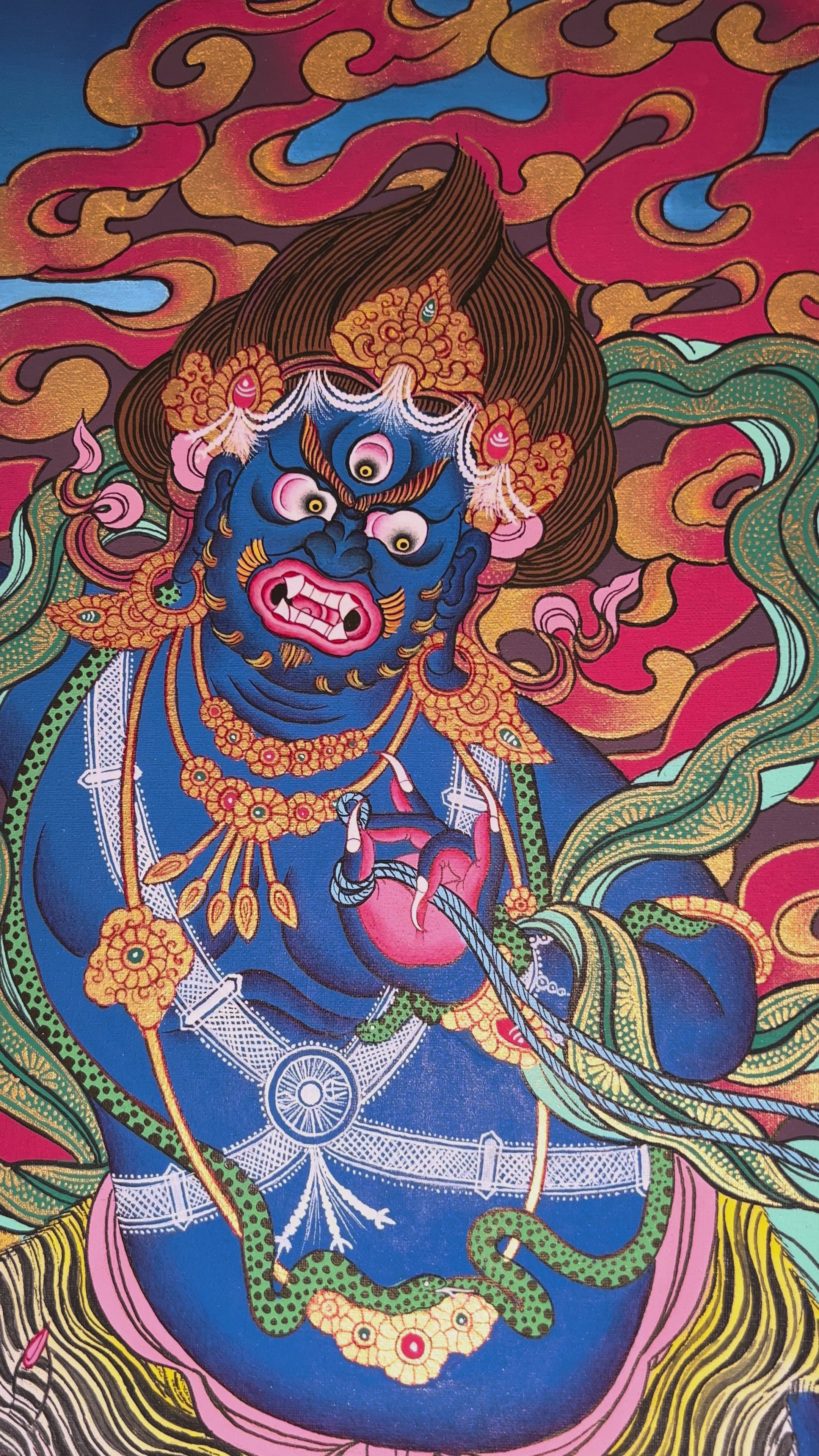 Vajrapani thangka showing a blue wrathful deity holding a vajra, surrounded by flames, standing dynamically on a lotus base in traditional Tibetan style.